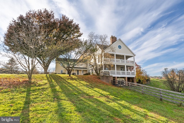 rear view of property featuring a balcony and a lawn