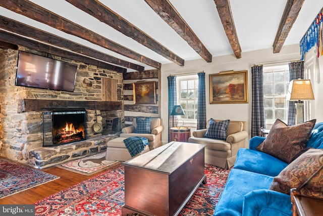 living room with wood-type flooring, beamed ceiling, and a fireplace