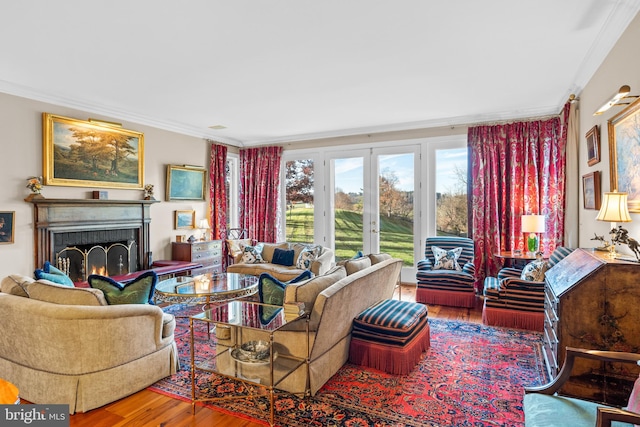 living room featuring french doors, crown molding, a brick fireplace, and hardwood / wood-style floors