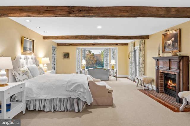 bedroom with beamed ceiling, a brick fireplace, and carpet floors