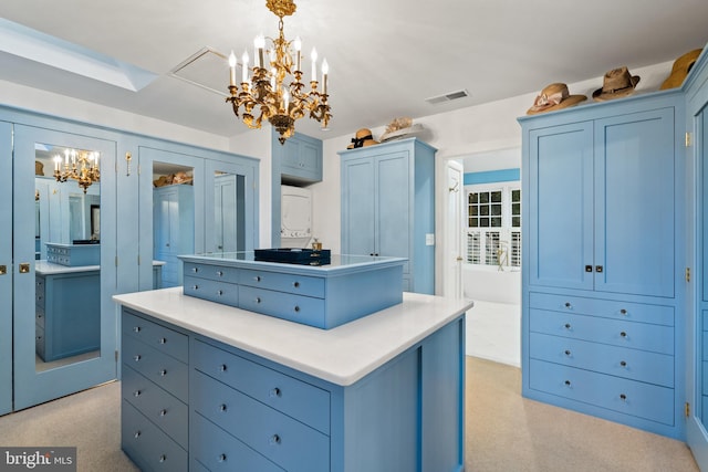 walk in closet with light carpet and a notable chandelier