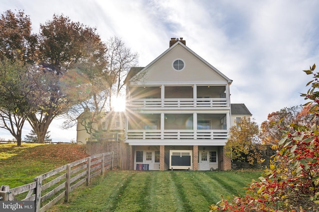 back of house featuring a yard, a sunroom, and a balcony