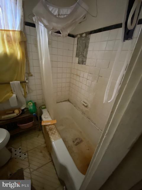 bathroom with a shower with curtain, toilet, and tile patterned floors