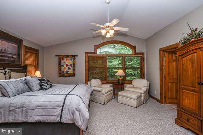 bedroom featuring ceiling fan, light carpet, and lofted ceiling