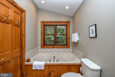 bathroom with toilet, a bathtub, and lofted ceiling