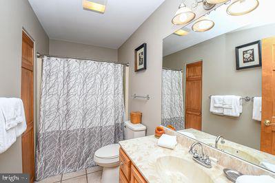 bathroom featuring tile patterned floors, a shower with curtain, vanity, and toilet