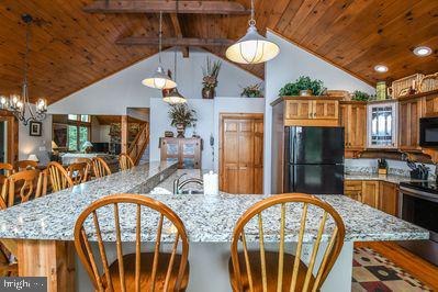 kitchen featuring light stone countertops, black appliances, a notable chandelier, wooden ceiling, and hanging light fixtures