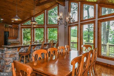 dining area featuring light wood-type flooring, wood ceiling, high vaulted ceiling, an inviting chandelier, and beamed ceiling