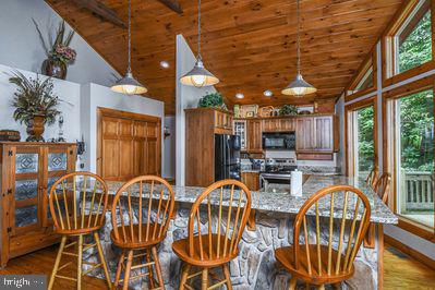 dining area with wood-type flooring, high vaulted ceiling, and wooden ceiling