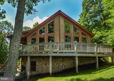 rear view of property featuring a deck and a lawn