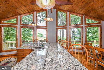 kitchen with hardwood / wood-style floors, sink, vaulted ceiling, ceiling fan, and light stone counters