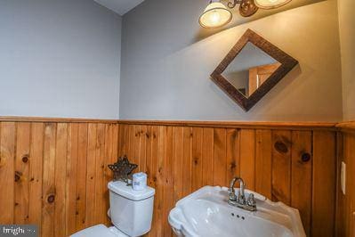 bathroom featuring wood walls, sink, and toilet