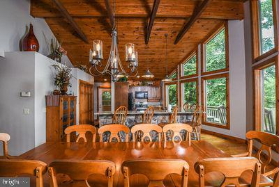 dining space with beam ceiling, wooden ceiling, plenty of natural light, and a notable chandelier