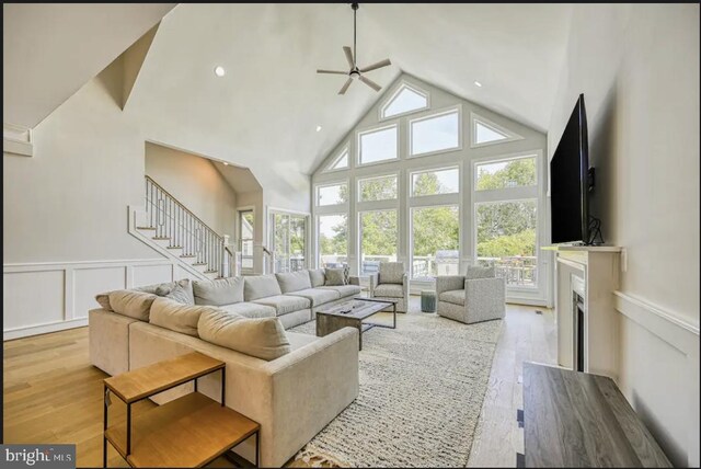 living room with light hardwood / wood-style floors, high vaulted ceiling, and ceiling fan