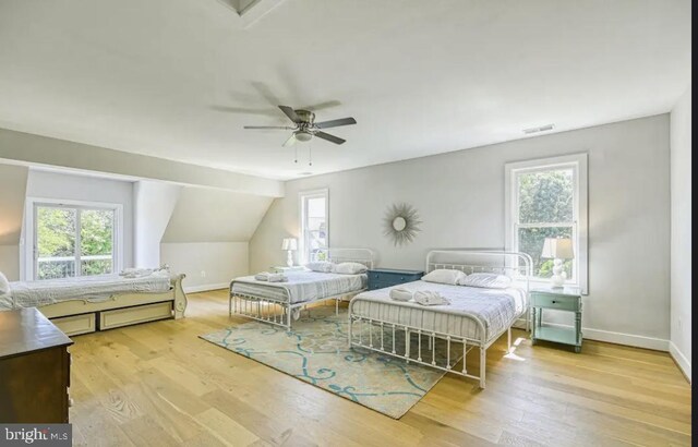 bedroom featuring ceiling fan, multiple windows, and light hardwood / wood-style flooring