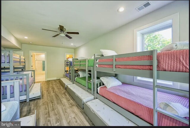 bedroom featuring hardwood / wood-style flooring, ensuite bathroom, and ceiling fan