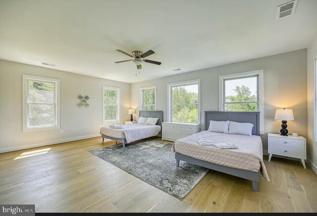 bedroom featuring ceiling fan, light hardwood / wood-style floors, and multiple windows