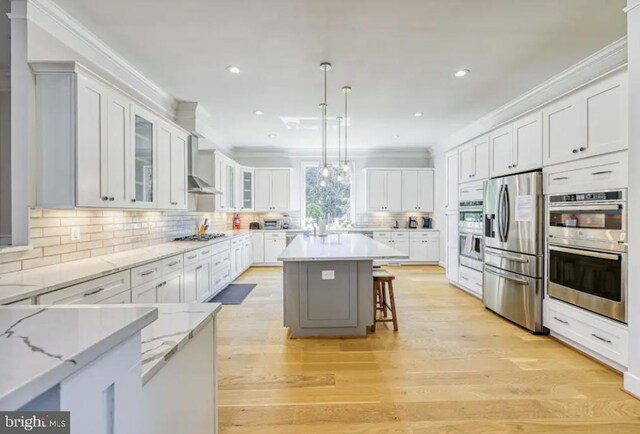 kitchen with hanging light fixtures, appliances with stainless steel finishes, white cabinets, a center island, and a breakfast bar area