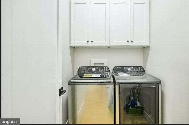 clothes washing area featuring washer and clothes dryer and cabinets