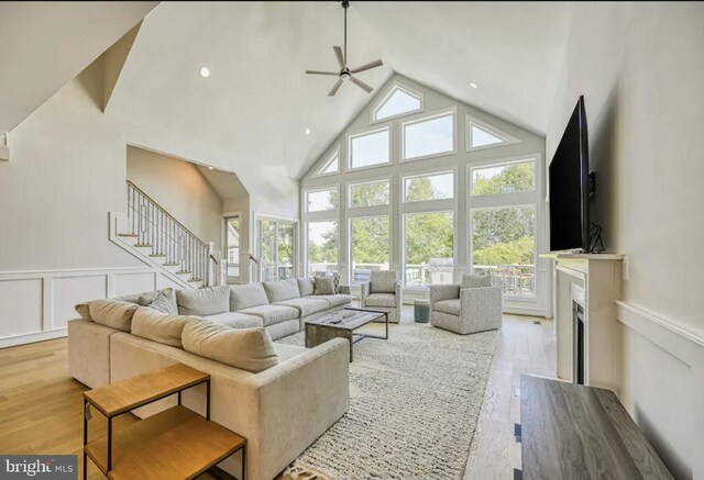 living room featuring high vaulted ceiling, light hardwood / wood-style flooring, and ceiling fan