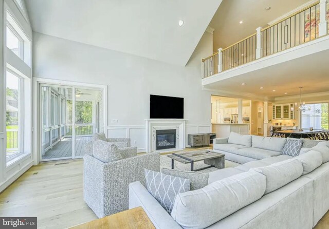 living room featuring a chandelier, a high ceiling, and light hardwood / wood-style flooring