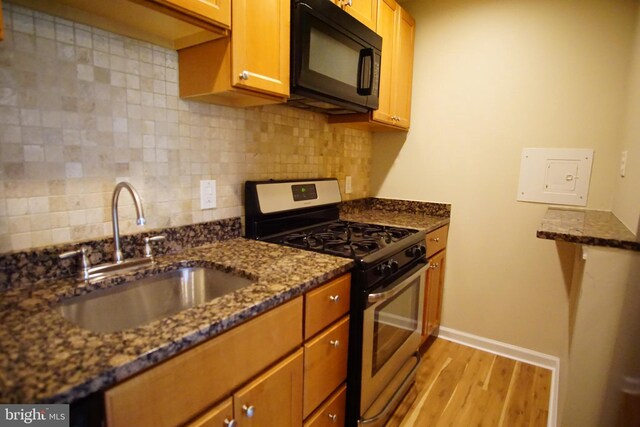 kitchen featuring black microwave, a sink, light wood-style floors, gas range, and backsplash