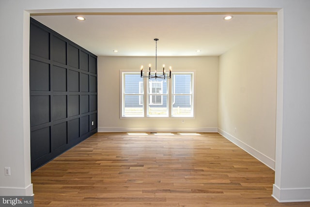 unfurnished dining area with hardwood / wood-style floors and an inviting chandelier