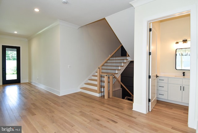 foyer entrance featuring light hardwood / wood-style floors, ornamental molding, and sink