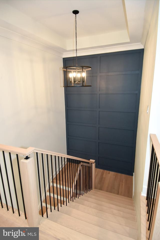 stairs with wood-type flooring and an inviting chandelier