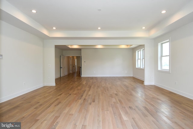 spare room with a raised ceiling and light hardwood / wood-style flooring