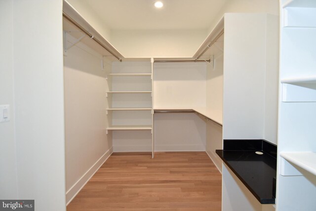 walk in closet with light hardwood / wood-style floors