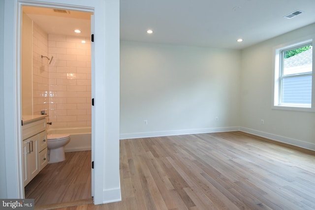 full bathroom with vanity, wood-type flooring, tiled shower / bath combo, and toilet