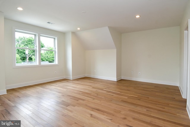 additional living space with light wood-type flooring and vaulted ceiling