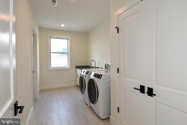 laundry room featuring sink, light wood-type flooring, and independent washer and dryer