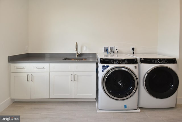 clothes washing area with sink, cabinets, light wood-type flooring, and independent washer and dryer