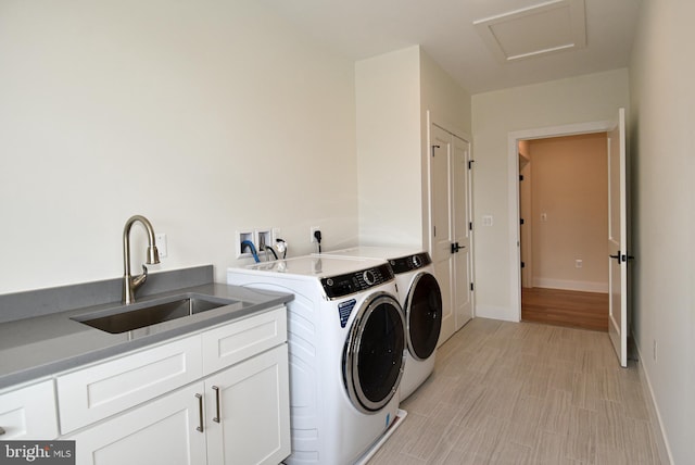 washroom with washing machine and clothes dryer, sink, cabinets, and light wood-type flooring