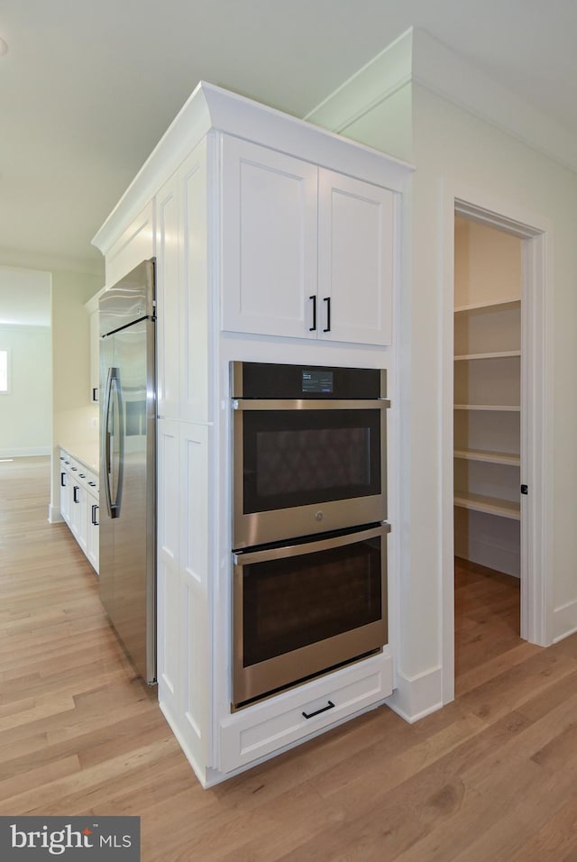 kitchen with white cabinets, light hardwood / wood-style floors, and appliances with stainless steel finishes