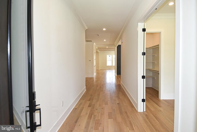 hallway with light hardwood / wood-style flooring and ornamental molding