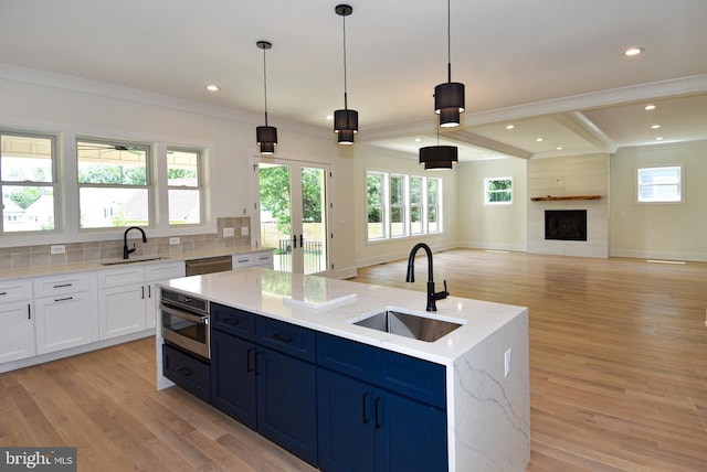 kitchen featuring hanging light fixtures, an island with sink, light hardwood / wood-style floors, and sink