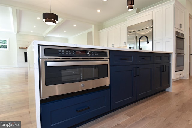 kitchen with appliances with stainless steel finishes, crown molding, decorative light fixtures, white cabinets, and light hardwood / wood-style floors