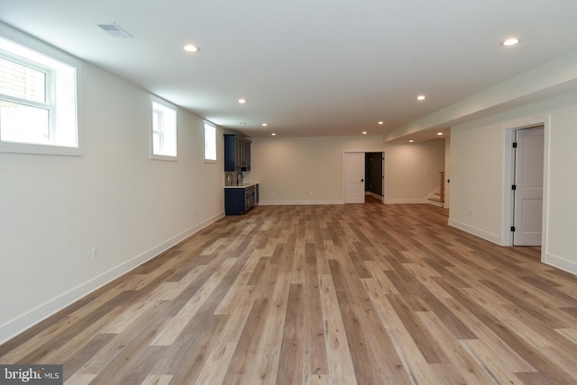 basement with light hardwood / wood-style flooring and sink