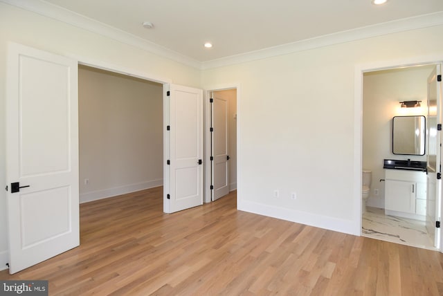 unfurnished bedroom featuring light wood-type flooring, connected bathroom, and crown molding