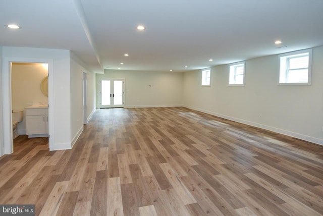 basement with french doors and light hardwood / wood-style flooring