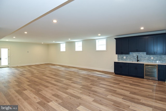 interior space featuring decorative backsplash, light hardwood / wood-style floors, beverage cooler, and sink