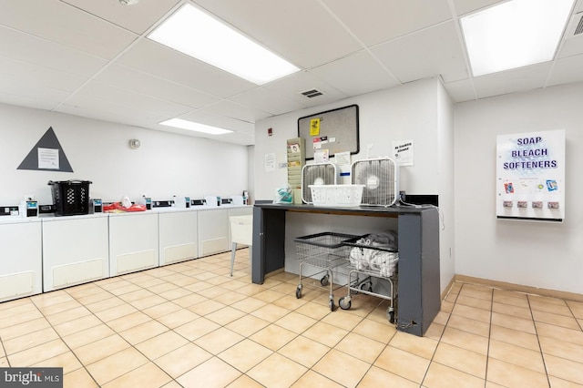 interior space with independent washer and dryer, a paneled ceiling, and light tile patterned floors