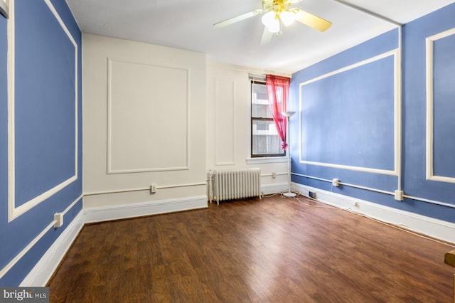 spare room featuring ceiling fan, radiator heating unit, and dark hardwood / wood-style flooring