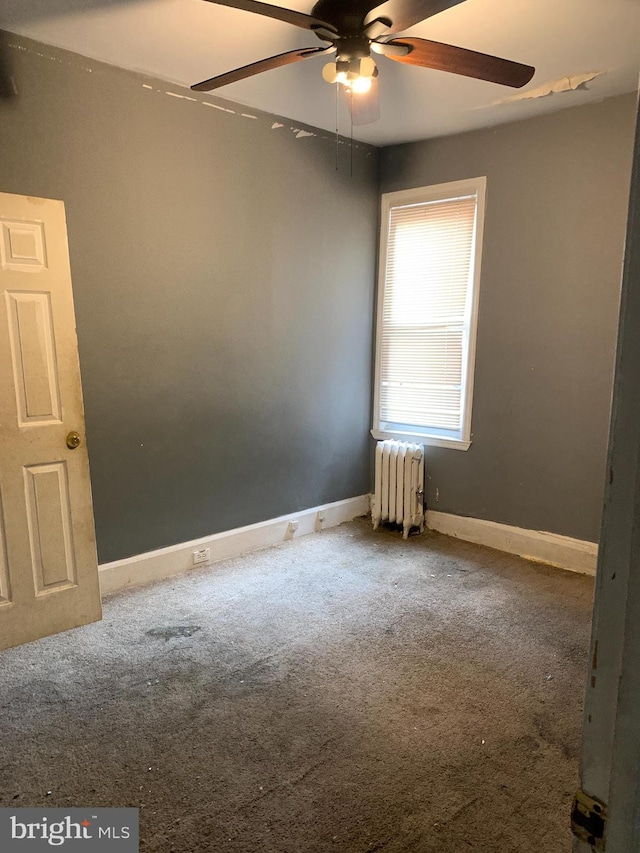 carpeted spare room featuring radiator heating unit and ceiling fan