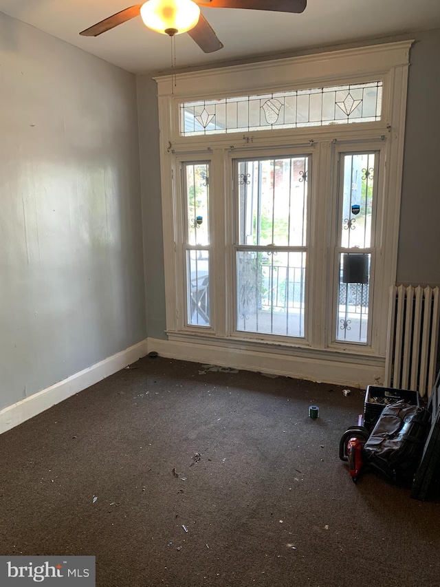 spare room with a wealth of natural light, carpet, radiator, and ceiling fan