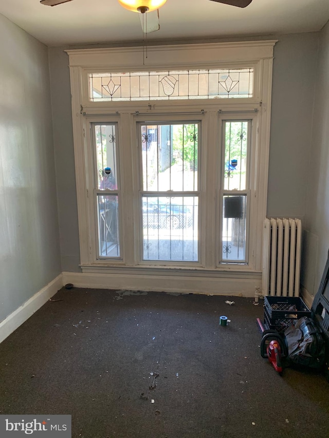 unfurnished room featuring radiator heating unit and ceiling fan