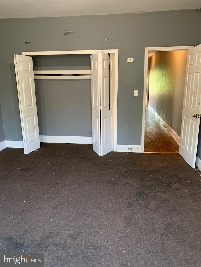 unfurnished bedroom with a closet and dark carpet